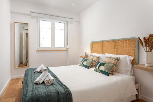 una camera da letto con un grande letto bianco con asciugamani di Lisbon Zoo House III a Lisbona