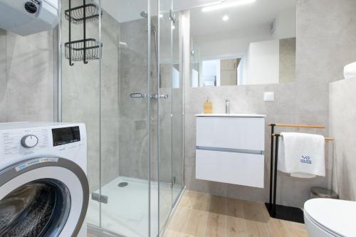 y baño con ducha y lavadora. en Apartament Perłowy by Major Domus Club, en Dziwnów