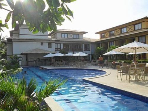 um resort com uma piscina com mesas e guarda-sóis em Cond Enseada - Belissímo Vista Mar na Praia do Forte na Praia do Forte