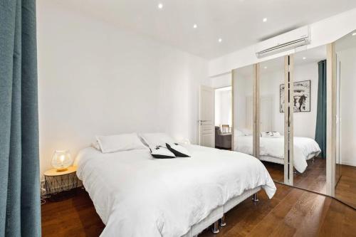 une chambre blanche avec un grand lit et un miroir dans l'établissement La Cachette du Port! -Avec parking au Port de Nice, à Nice