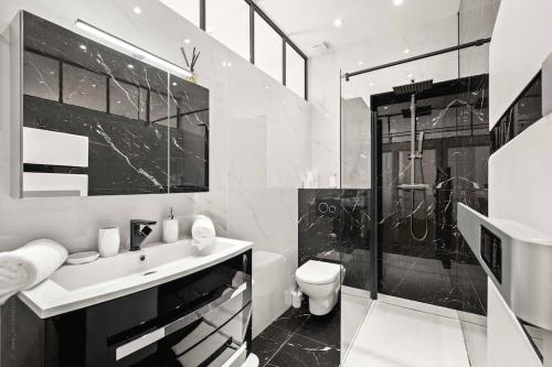 a black and white bathroom with a sink and a shower at La Cachette du Port! -Avec parking au Port de Nice in Nice