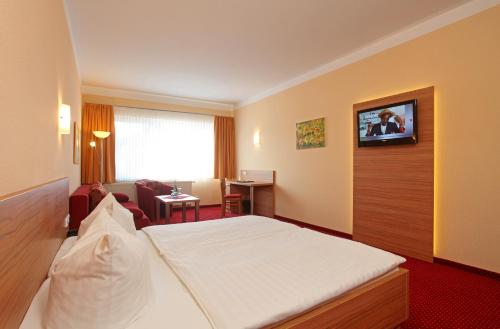 a hotel room with a bed and a television at Sporthotel Neuruppin in Neuruppin