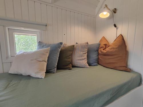 a couch with many pillows on it in a room at Tranum Klit Camping og Hytteudlejning in Brovst