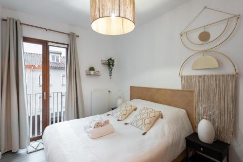 une chambre avec un lit avec des draps blancs et une fenêtre dans l'établissement Le Conflu Home - En plein cœur de la Confluence, à Lyon