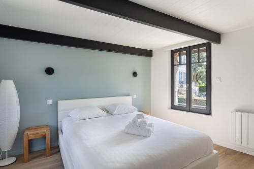 une chambre avec un grand lit blanc et une fenêtre dans l'établissement La Fleur du Moulin - Charmante maison avec jardin proche plage, à Saint-Briac-sur-Mer
