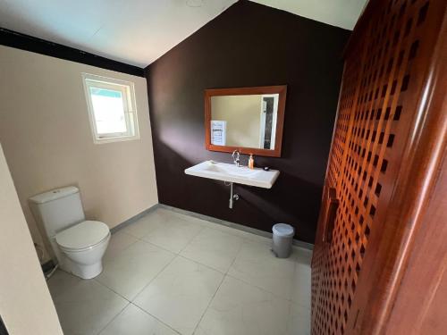 a bathroom with a white toilet and a sink at The Farmhouse Mahaulpatha in Bandarawela