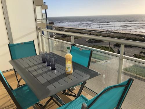 - une bouteille de vin sur une table sur un balcon donnant sur la plage dans l'établissement Appartement 2 pièces, balcon vue mer, parking privé, plage des Demoiselles - FR-1-224C-27, à Saint-Hilaire-de-Riez