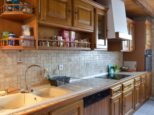 une cuisine avec des armoires en bois et un évier dans l'établissement Maison climatisée 4 pièces, 8 couchages, proche plage et commerces, avec véranda et barbecue - FR-1-229D-113, à Fleury