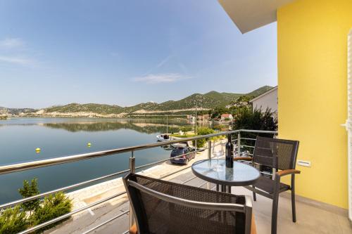 a balcony with a table and chairs and a view of the water at Apartments Ema in Rogotin