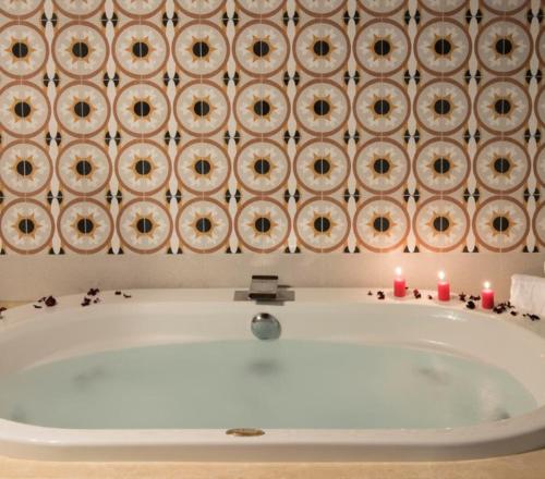 a bath tub in a room with candles on the wall at Colle Indaco Wine Resort & Spa in Ortezzano
