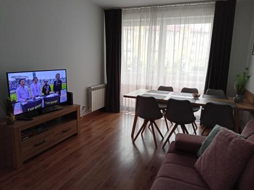 een woonkamer met een televisie en een tafel en stoelen bij APARTAMENT RELAX in Ełk