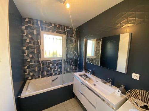 une salle de bain avec un lavabo, une baignoire et un miroir dans l'établissement Maison la teste centre, à La Teste-de-Buch