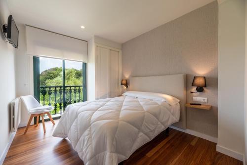 Un dormitorio con una gran cama blanca y una ventana en Hostal Devesas en O Grove