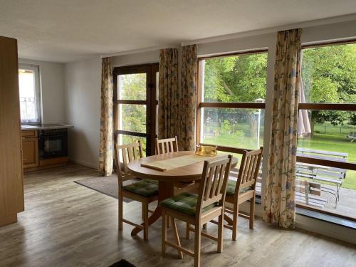 a dining room with a table and chairs and windows at FEWO am See Zarrendorf in Zarrendorf