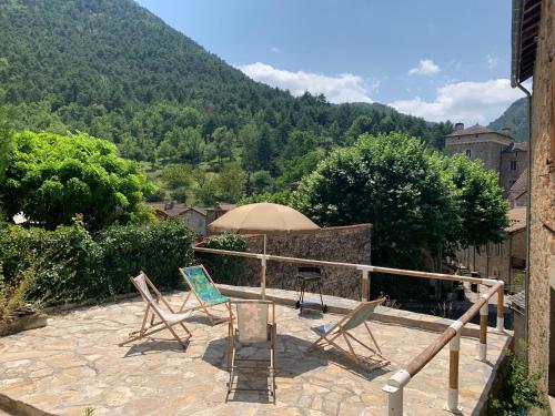 a patio with two chairs and an umbrella at GITE AVEC GRANDE TERRASSE in Peyreleau