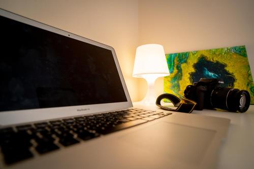 un ordinateur portable assis sur un bureau avec une lampe et une caméra dans l'établissement Casa dello Studente, à Vittorio Veneto