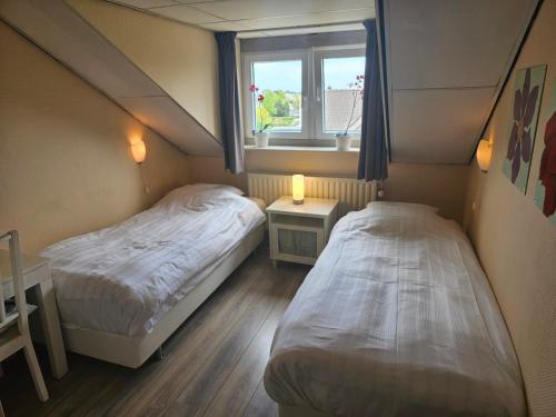 two beds in a small room with a window at hotel le bonheur in Eijsden