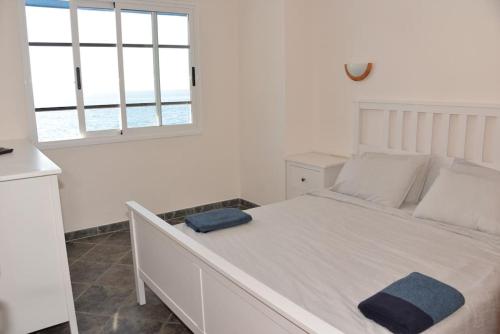 Beachfront Apartment - Tacoronte في سانتا كروث دي تينيريفه: غرفة نوم مع سرير أبيض كبير مع نافذة
