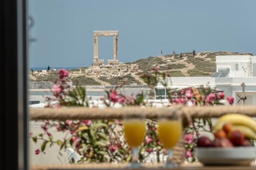 a plate of fruit and glasses of orange juice on a balcony at Venetian Suites III in Naxos Chora