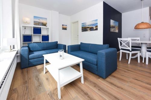 a living room with two blue couches and a table at Ferienwohnungen Blaues Haus in Bensersiel