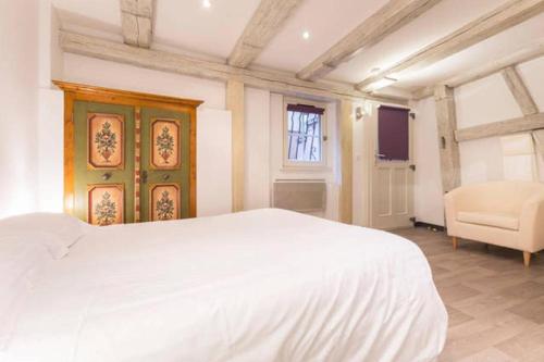 une chambre avec un grand lit blanc et une chaise dans l'établissement Historic city center - Petite Venise suites, à Colmar