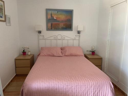 um quarto com uma cama com uma colcha rosa em Los Maites 2- Estudio em Benalmádena