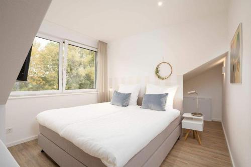 Un dormitorio blanco con una cama grande y una ventana en SEASIDE - Neubau mit Meeresblick en Sierksdorf