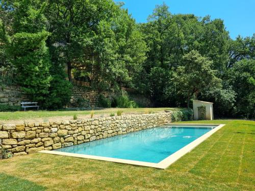 - une piscine dans une cour à côté d'un mur en pierre dans l'établissement Magnifique Mas Provençal, à Lauris
