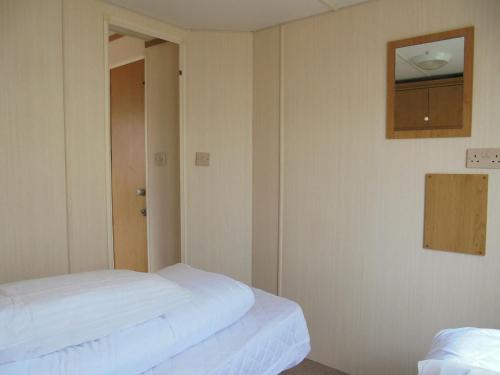 a room with two beds and a mirror on the wall at Promenade: Retreat:- 4 Berth, Access to the beach in Ingoldmells