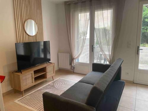 ein Wohnzimmer mit einem Sofa und einem Flachbild-TV in der Unterkunft LE TEMPS D UNE PAUSE avec jardin accès au canal du midi in Castelnaudary
