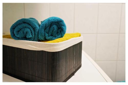 a brown basket with blue towels in a bathroom at Ingrid’s Guesthouse Spittal in Spittal an der Drau