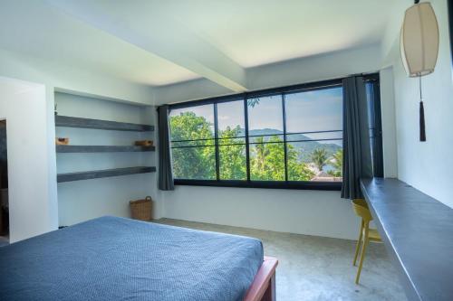 1 dormitorio con cama azul y ventana grande en Banana Villa Koh Tao en Ko Tao