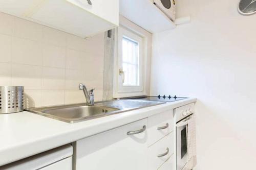 une cuisine blanche avec un évier et une fenêtre dans l'établissement Historic city center - Petite Venise suites, à Colmar