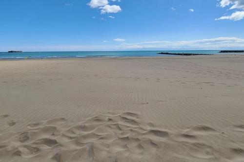 une plage de sable et d'océan avec des vagues dans l'établissement Proche plage - Pavillon de vacances Ohana & jardin - Richelieu, au Cap d'Agde