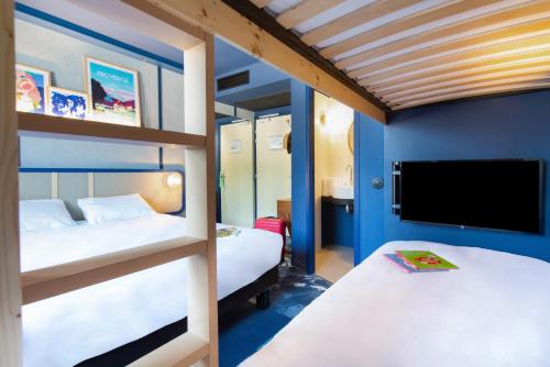 greet hotel Salon de Provence في صالون دو بروفانس: غرفة نوم بسريرين بطابقين وتلفزيون بشاشة مسطحة