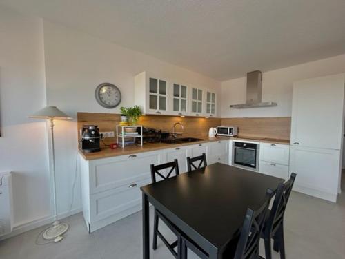 une cuisine avec des placards blancs et une table et des chaises noires dans l'établissement Appartement T2 cabine avec parking sécurisé à 200m de la plage - FR-1-388-178, à Argelès-sur-Mer