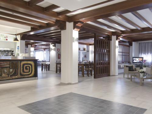 a large room with wooden ceilings and tables and chairs at Hotel Nettuno in Cala Gonone