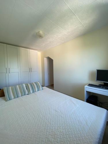 Schlafzimmer mit einem weißen Bett und einem Schreibtisch in der Unterkunft Penthouse located very close to the city center in Tallinn