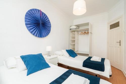 two beds in a white room with blue accents at Covelo Park Apartment in Porto