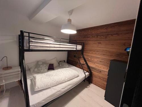 - une chambre avec des lits superposés et un mur en bois dans l'établissement Appartement en montagne 90m2 3 chambres, à La Chal