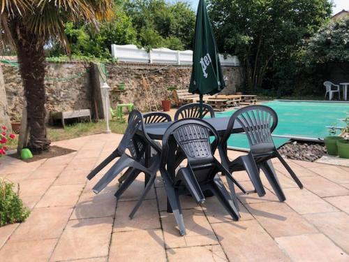 três cadeiras e uma mesa com um guarda-sol verde em Maison de famille em Saint-Mars-dʼOutillé
