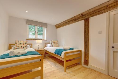 a bedroom with two beds and a window at Owl Barn in Morston