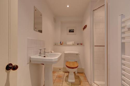 a white bathroom with a sink and a toilet at Owl Barn in Morston