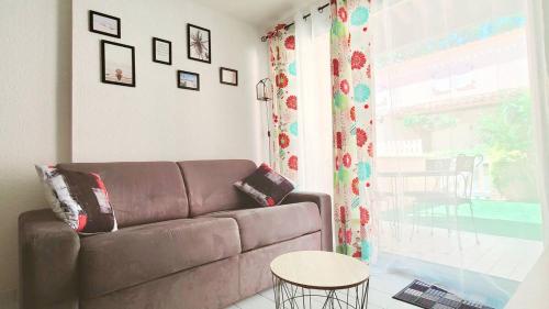 un salon avec un canapé marron et une fenêtre dans l'établissement Proche plage - Pavillon de vacances Ohana & jardin - Richelieu, au Cap d'Agde