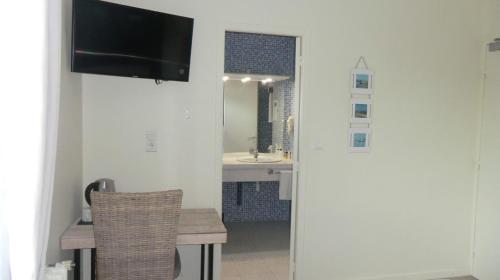 ein Badezimmer mit einem Waschbecken, einem Tisch und einem TV in der Unterkunft Hôtel Le Boïate in Arès