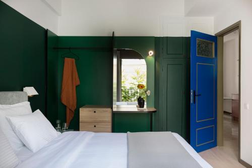 een slaapkamer met groene muren en een blauwe deur bij Nileos House in Athene