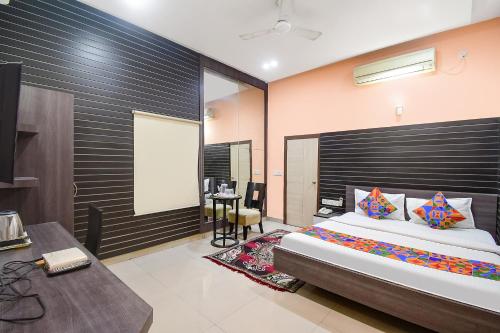 a bedroom with a bed and a desk and a table at FabExpress Gardenia in Ballygunge