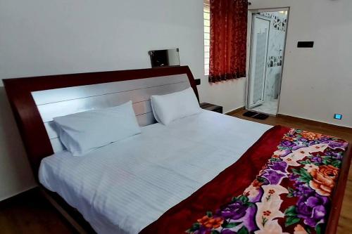 a bedroom with a large white bed with a floral blanket at iSTAYS - Luxe Villa, Yercaud in Yercaud