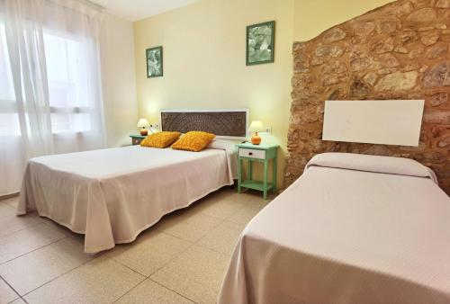 a bedroom with two beds and a stone wall at Hostal Noray in Sant Feliu de Guíxols