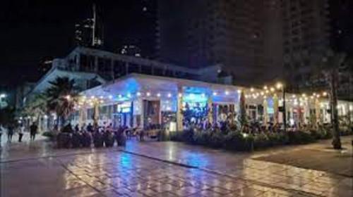 a lit up building with people sitting outside at night at חופים מול הים in Bat Yam